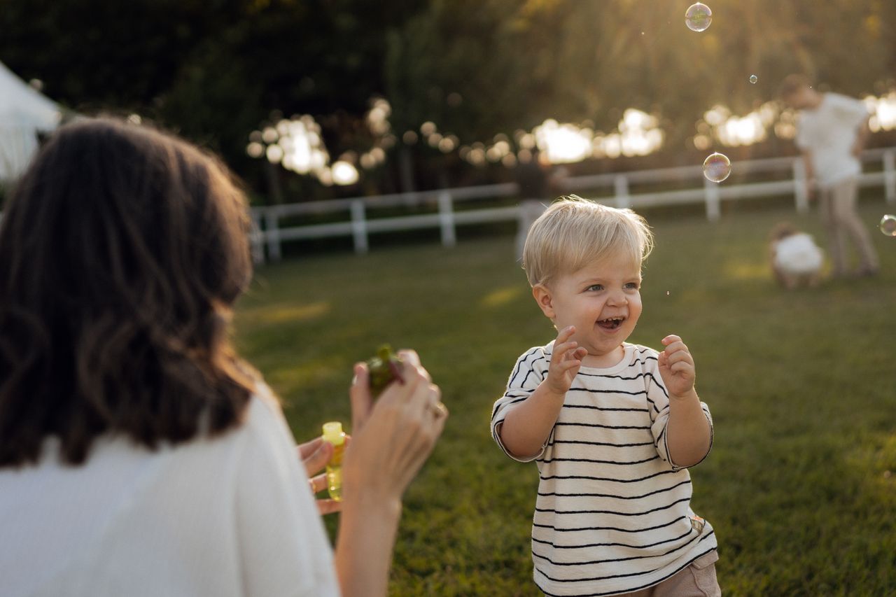 Delighted toddler playing with bubbles in the sunlit park, capturing childhood joy.