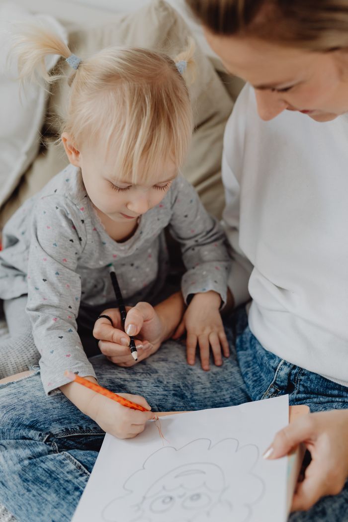A mother and her toddler daughter drawing together, fostering creativity and family bonding.